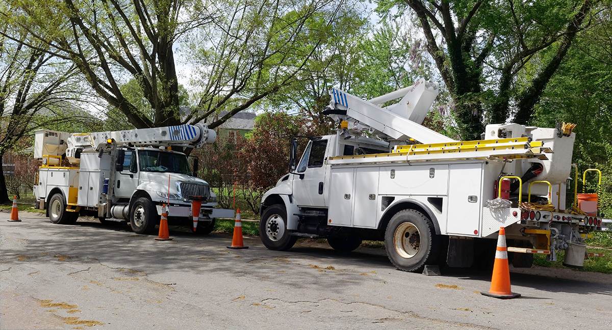 Parked utility work trucks on residential street after storm.