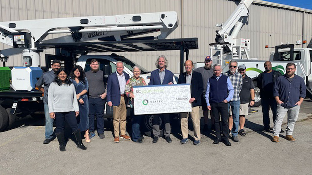 A group of Viatec team members and SC Launch Inc. representatives stand proudly in front of a utility vehicle, holding an oversized ceremonial check for $300,000, symbolizing the investment in Viatec's sustainable fleet solutions.