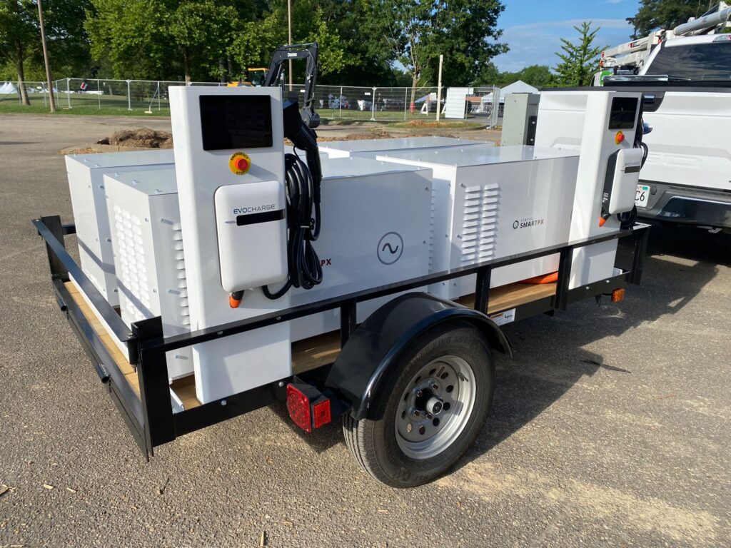 Mobile EV charging trailer featuring Evocharge station and SmartPX power system. Compact, trailer-mounted solution for on-site electric vehicle charging and mobile power distribution. White equipment on black trailer frame, showcasing portable clean energy technology for fleet and worksite applications.